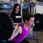 woman performing power squat exercise with barbell on shoulders