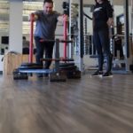 female trainer with male client pushing rolling weight cart across floor