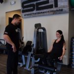 male trainer with female client on leg extension machine