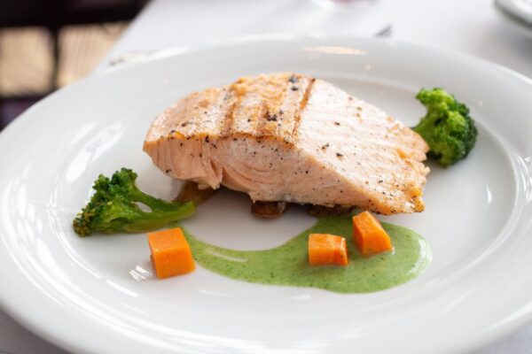 salmon filet with small portion of vegetables in green sauce
