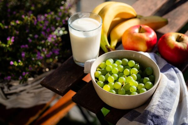 whole food options, including: bowl of green grapes, bananas, applies, leafy greens, carrots, and glass of milk